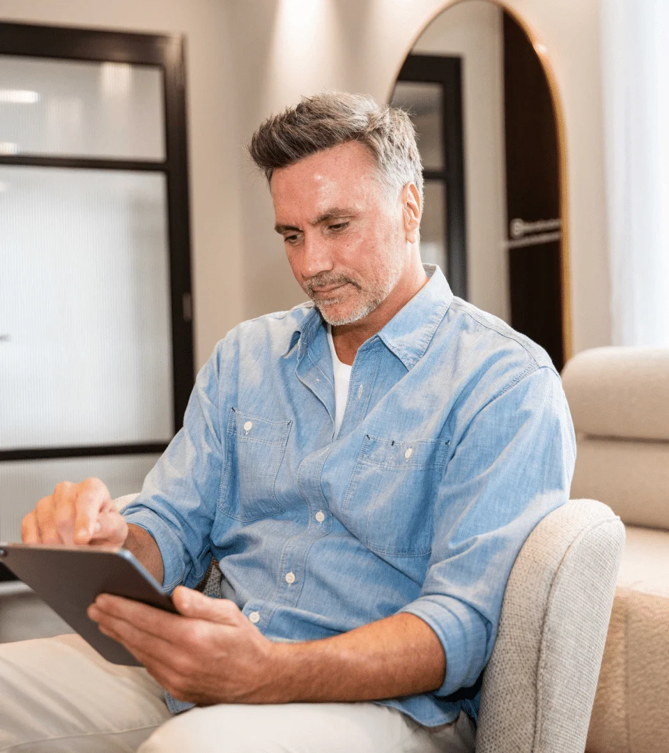 Patient relaxing with a tablet in the waiting area at Couture Implant Centre